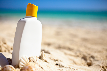 Bottle of suncreen on a sunny beach beside the ocean.